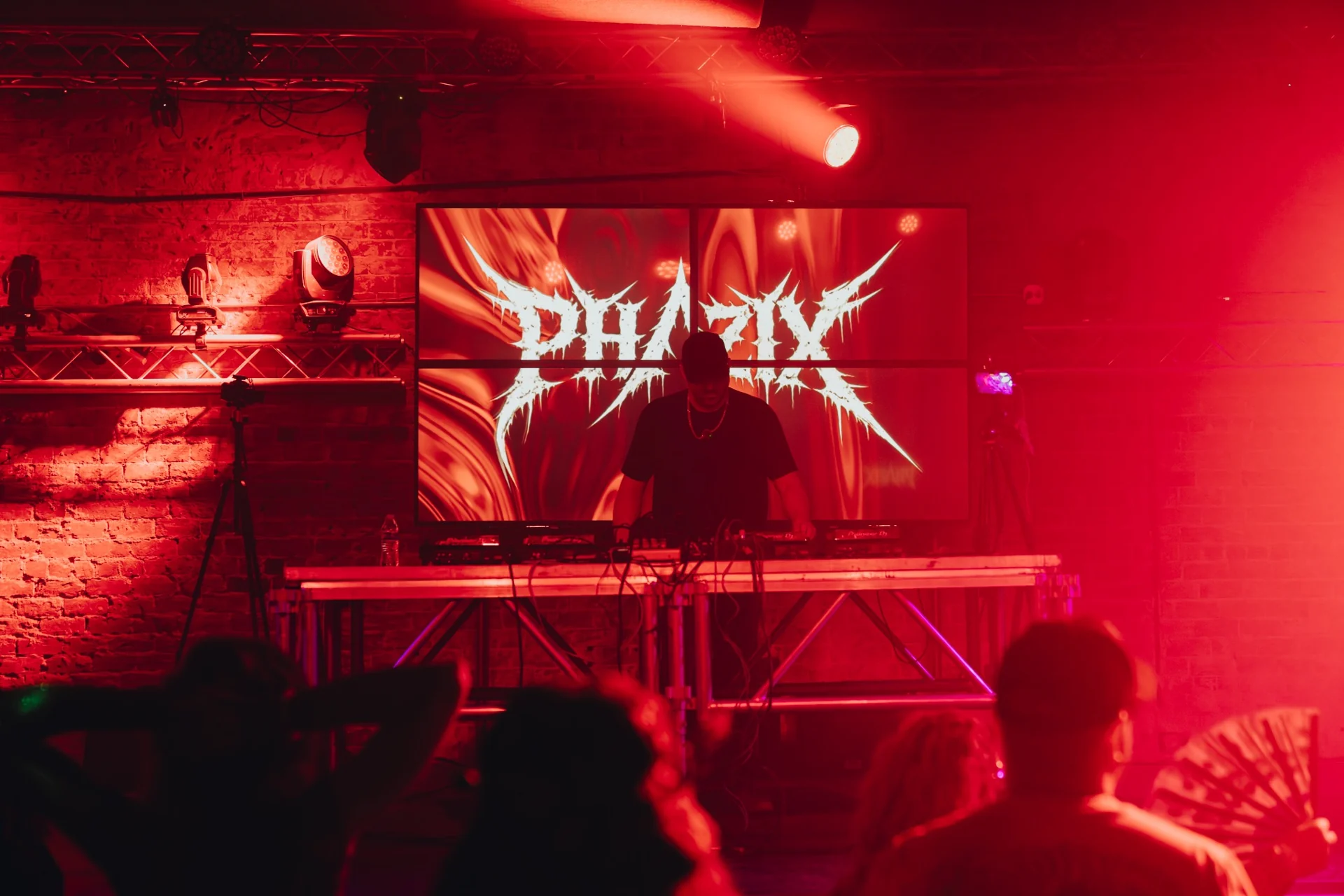 PHAZIX at the decks with a red-lit stage behind him